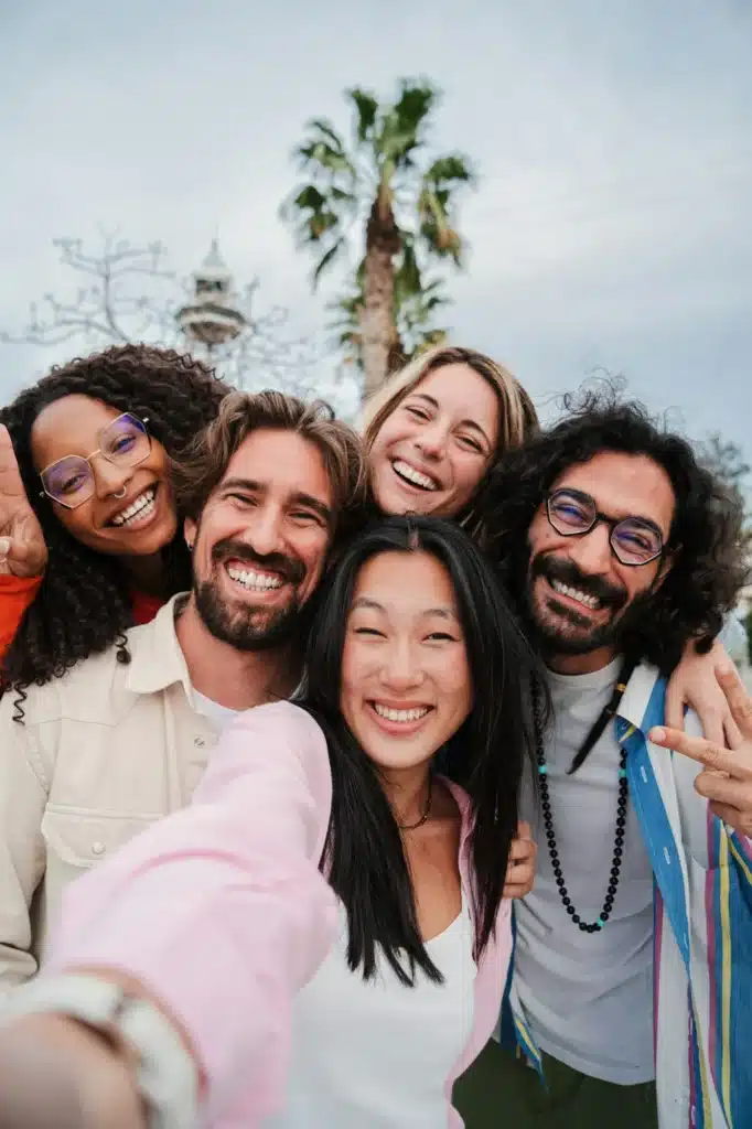 Vertical portrait of a group of joyful young friends taking a selfie smiling looking at camera