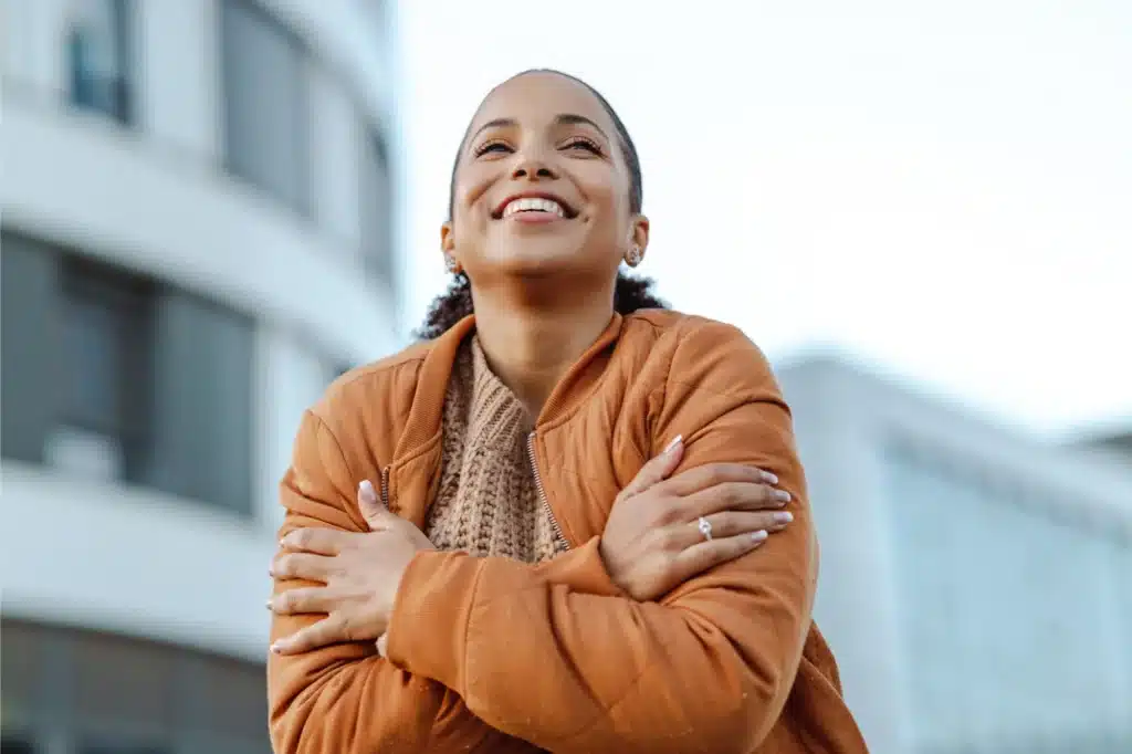 Person embracing themselves outdoors confidently.