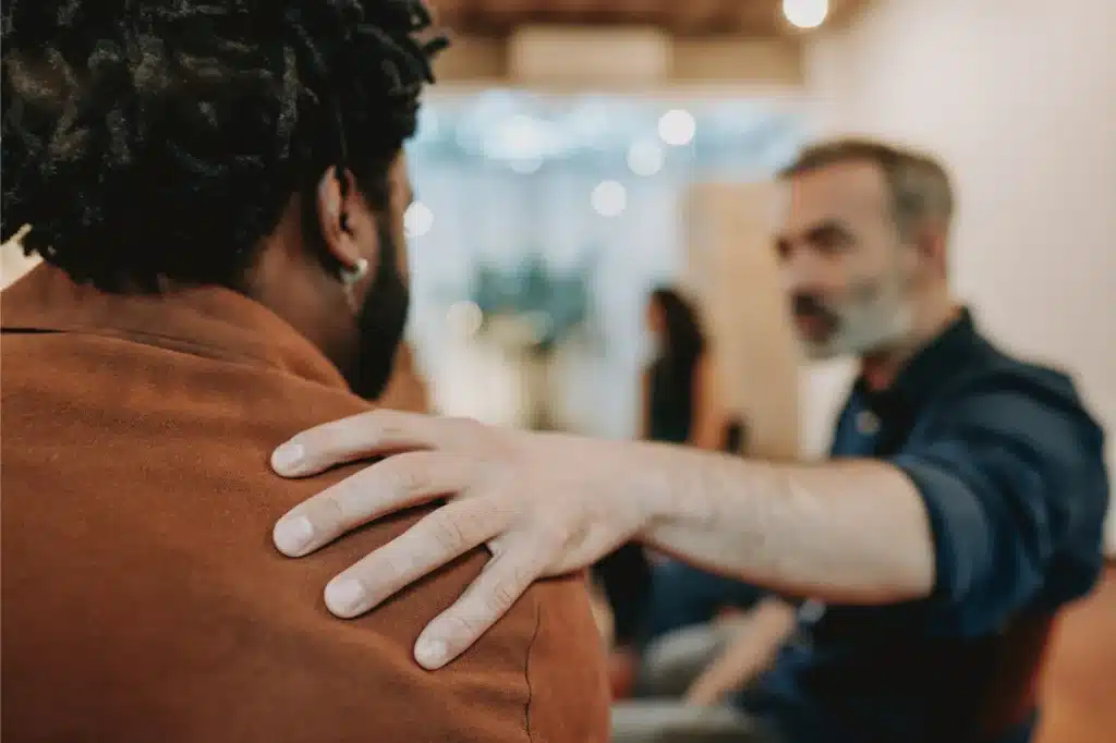 Two friends supporting each other at an alcoholism treatment facility.