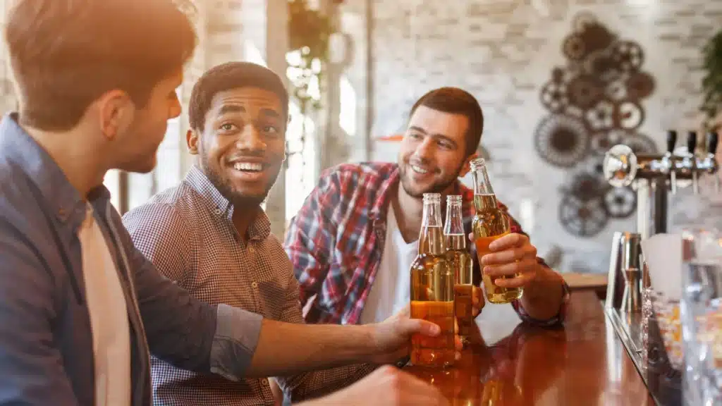 Stock image of social drinking culture combined with overlays of alcohol ads and trending hashtags, representing media influence on alcohol perception.