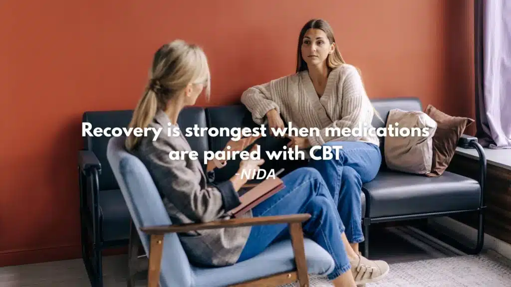 Stock photo of therapy session showing counselor and client, with medication and recovery journal in view.