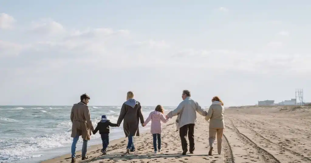 Family walking hand-in-hand on beach.
