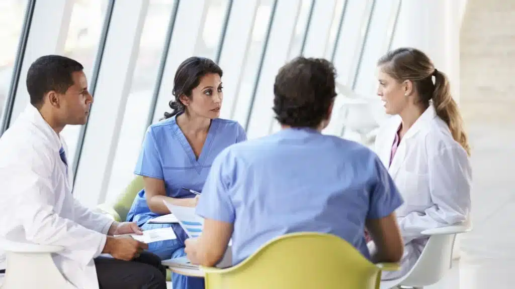 Addiction treatment doctor leading a care team meeting in a modern medical office in New Jersey.