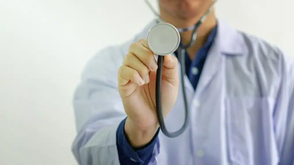 Healthcare professional using a stethoscope with heart and liver illustration overlay, representing alcohol-related health risks.