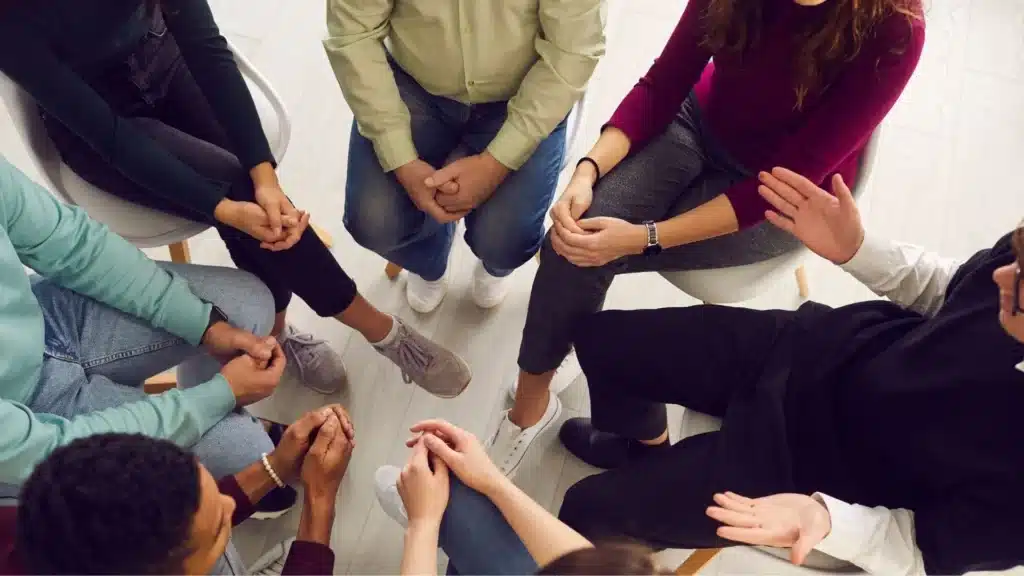 Therapy group sitting in a circle in bright natural light, symbolizing hope and support in alcohol recovery.