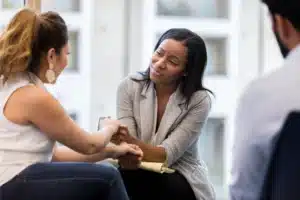 Therapist providing emotional support to a client during a counseling session in a drug rehabilitation program.