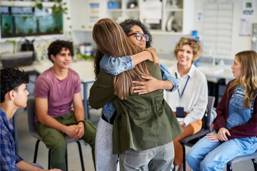 People embracing during outpatient alcohol treatment group therapy session.