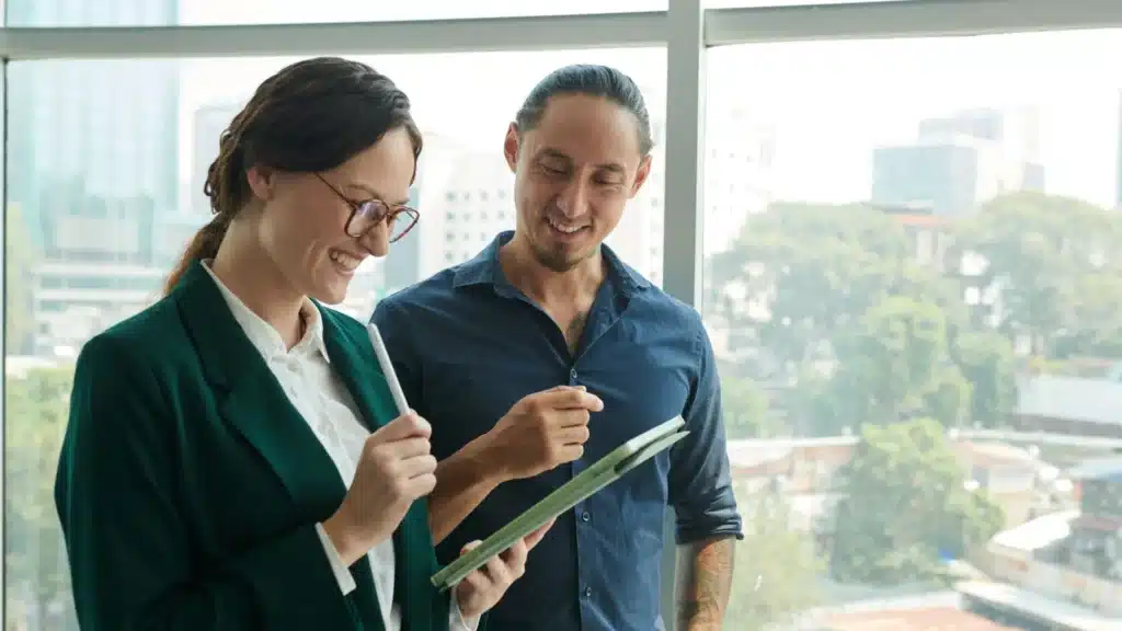 Two people smiling and reviewing intake paperwork during an admissions meeting at a private alcohol rehab center.