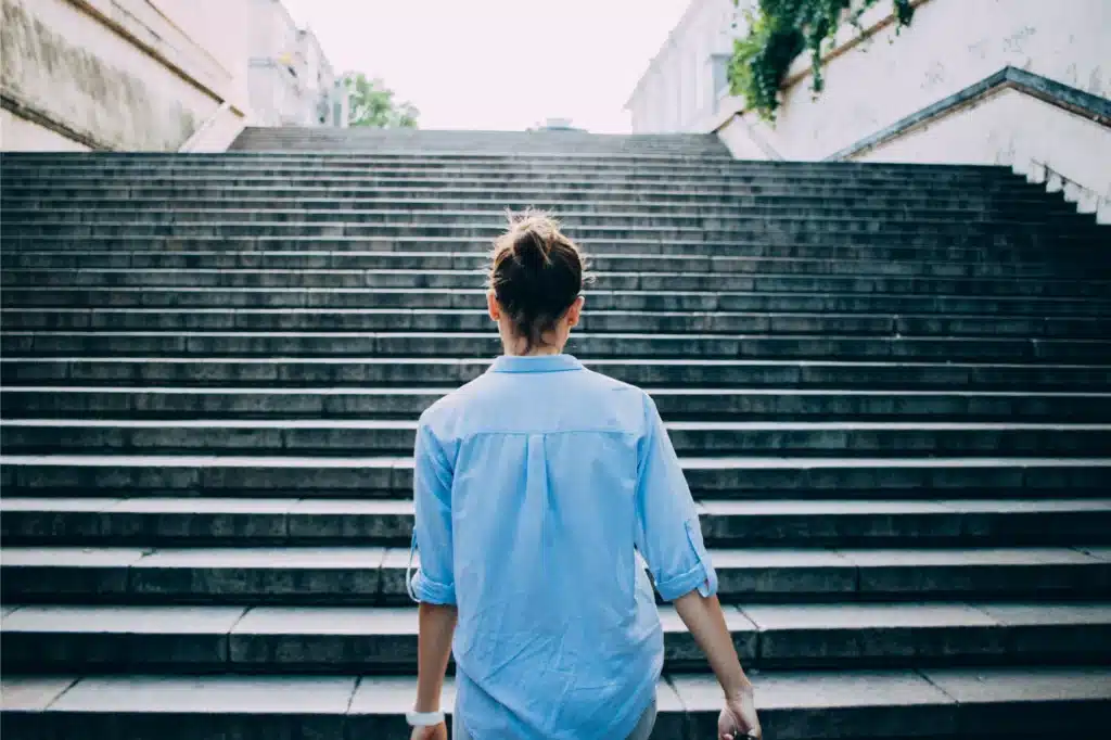 Individual preparing to climb stairs, representing the progressive stages of alcoholism and the path to recovery.