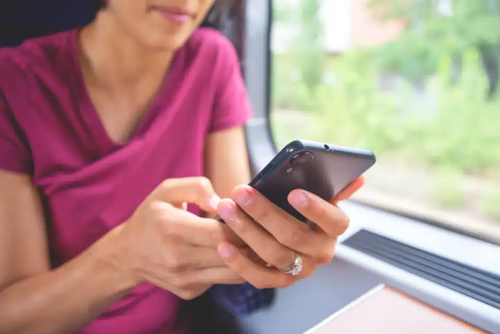 Person using a smartphone to access telehealth addiction recovery support or mental health resources.